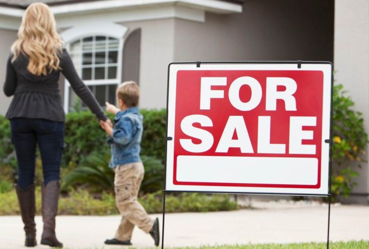 For sale sign in front yard of a home.